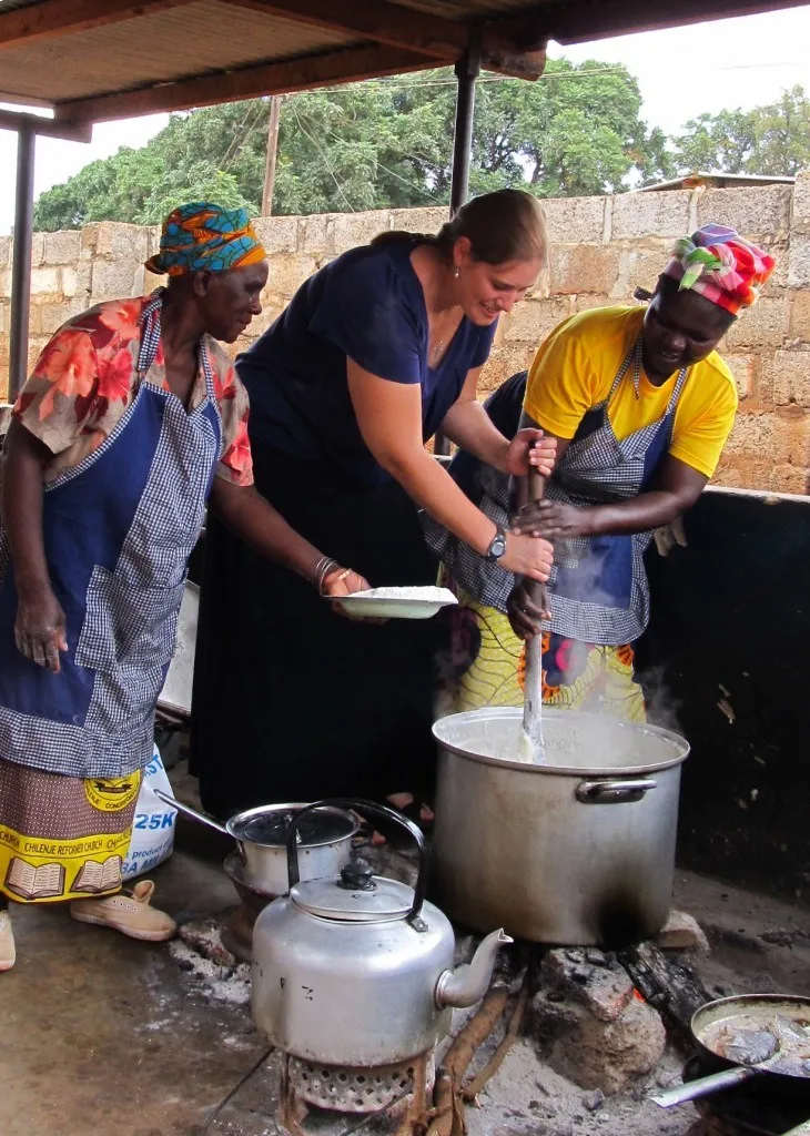 Women cooking nshima, a staple in Zambia, in a large pot.